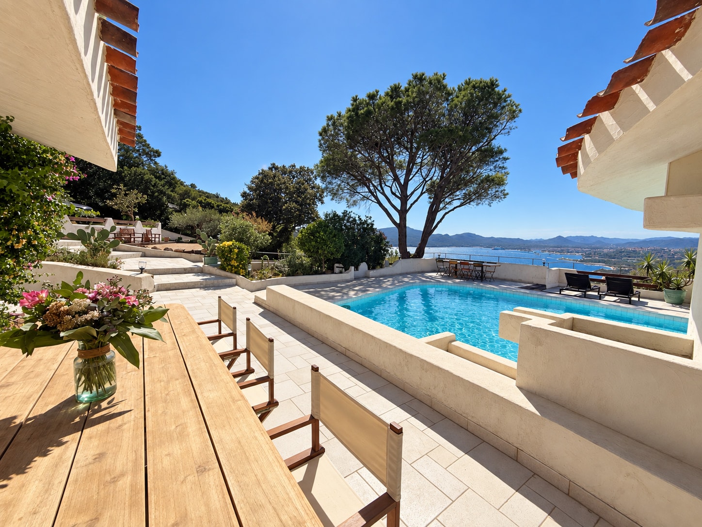 The long wooden table laid on the terrace, above the pool and the gulf
